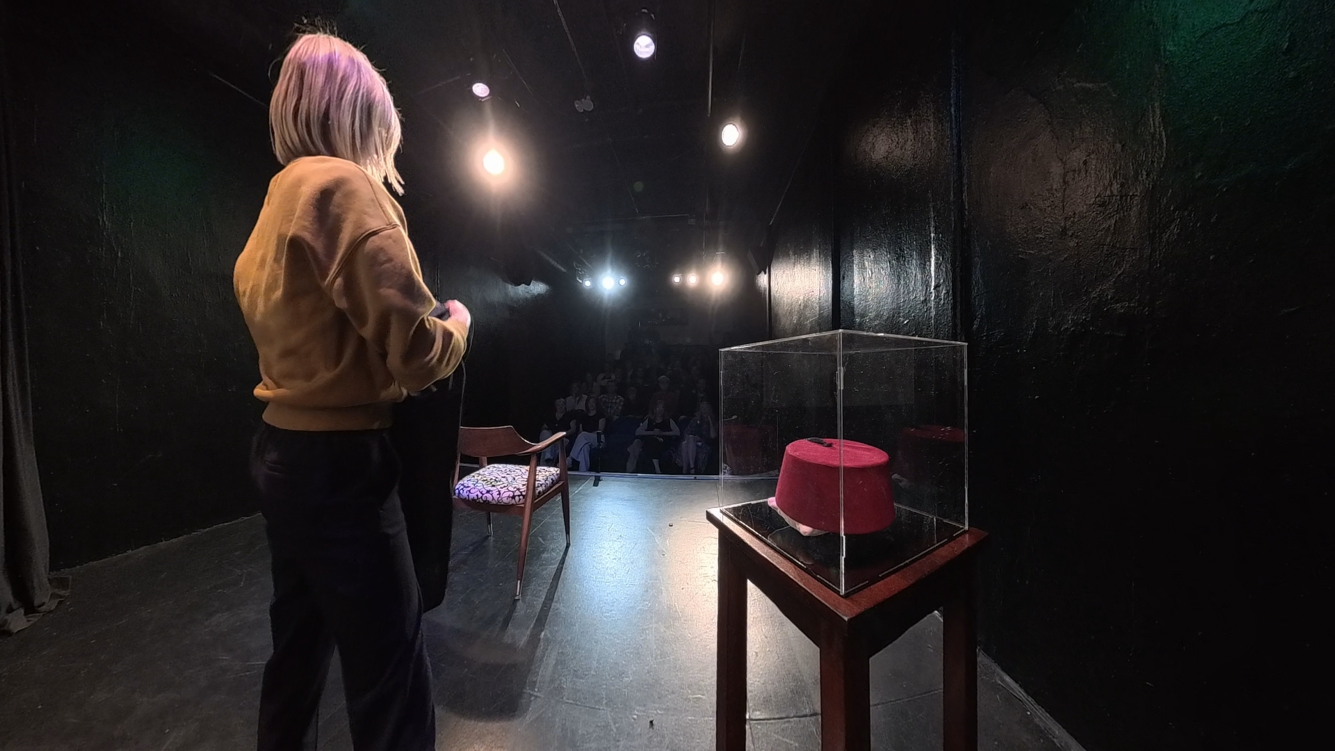 Over-the-shoulder view of the stage with a red fez displayed in a glass case